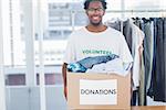Attractive man holding a donation box full of clothes