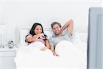 Couple watching tv together in their bed