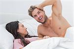 Shirtless man posing next to his sleeping partner in bed