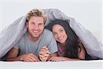 Cheerful couple under the cover in their bed