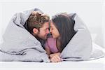 Couple wrapped in the duvet in bed