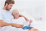 Father and his son using a tablet in bed