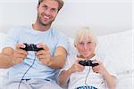 Father and son playing video games in bed