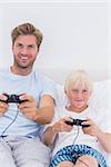 Happy father and son playing video games in bed