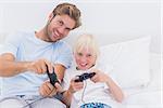 Cheerful father and son playing video games in bed