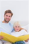 Portrait of a father reading a story to his son in bed