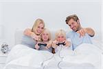 Happy family playing video games in bed