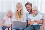 Cheerful family using a laptop sat on the couch