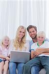 Portrait of a cheerful family using a laptop sat on the couch