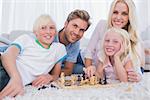 Smiling family playing chess together in the living room