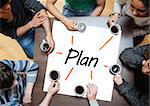 Team brainstorming around a table over a poster with plan written on it