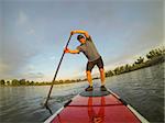 mature male paddler enjoying workout on stand up paddleboard (SUP), calm lake in Colorado, summer