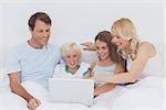 Family using a laptop in bed