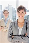 Two smiling businesswomen looking at camera with arms crossed in bright office