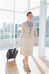 Businesswoman pulling her suitcase in large bright office