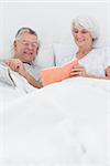 Mature woman showing her book to husband in bed