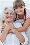 Young girl hugging her grandmother in the couch