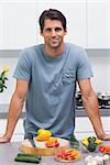 Attractive man standing in his kitchen in front of sliced vegetables
