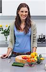 Attractive woman standing in her kitchen in front of sliced vegetables