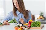 Pretty woman eating a vegetarian salad in the kitchen