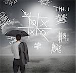Businessman looking at noughts and crosses and holding umbrella