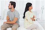 Couple sulking with arms crossed in bedroom