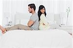 Couple sitting back to back during dispute in bedroom