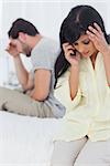 Woman calling someone during dispute with partner in bedroom