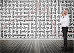 Thoughtful businessman standing and looking at a maze on a wall