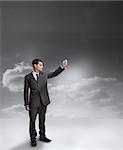 Businessman holding out his arm with clouds on the background
