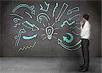 Businessman looking at a wall with drawings of arrows with a light bulb in the middle