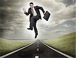 Businessman jumping on a road leading out to the horizon
