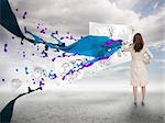 Businesswoman drawing on a paper next to paint splash with blue sky on the background
