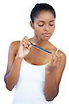 Serious young woman using nail file on white background