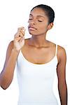 Young woman smelling her lip balm on white background