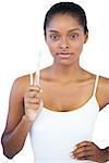 Woman with hand on hip holding her toothbrush on white background