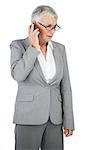 Unsmiling businesswoman calling someone with her mobile phone on white background