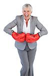 Happy businesswoman wearing boxing gloves on white background