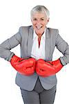 Cheerful businesswoman wearing boxing gloves on white background