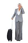 Serious businesswoman with her luggage and calling someone on white background