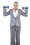 Concentrated businesswoman holding dumbbells on white background