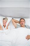 Woman blocking her ears because of partners snoring at home in bed