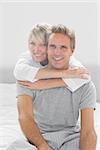 Loving couple looking at camera at home in bedroom