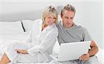 Couple using their laptop at home in bedroom