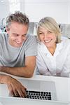 Smiling couple using their laptop in the morning sitting at kitchen counter