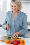 Smiling woman preparing vegetables at the kitchen counter