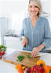 Cheerful woman chopping vegetables at the kitchen counter