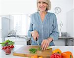 Happy woman chopping vegetables at the kitchen counter