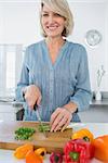Smiling woman chopping vegetables at the kitchen counter