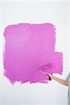 Woman painting her wall pink in a new home